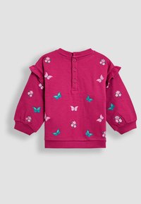 Ružový sweatshirt s vyšívanými motýľmi a kvetmi, s volánikmi na ramienkach a zapínaním na gombík na chrbte. Mäkká textúra látky.