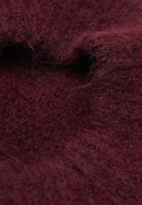 Bordová textúrovaná látka s jemným, chlpatým povrchom, charakteristická voľným tkaním a prírodnými vláknami, zdôrazňujúca teplý, sýty odtieň farby.