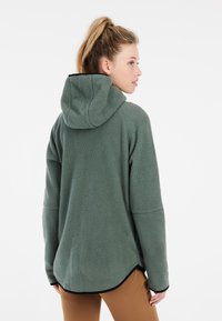 Groene fleece pullover met een capuchon, voorzien van een zachte textuur, een relaxte pasvorm en contrasterende zwarte afwerking aan de zoom en mouwen.
