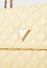 Borsa gialla trapuntata con texture liscia, caratterizzata da un logo triangolare in oro e tracolla a catena. Elegante motivo a rombi su tutta la superficie.