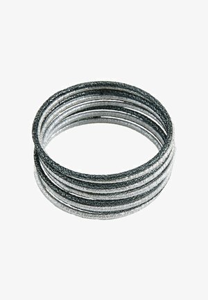 Ensemble d'élastiques à cheveux recouverts de tissu noir et argent empilés en alternance sur un fond blanc.