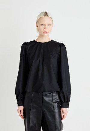 Black long-sleeve blouse made of smooth fabric, featuring a round neckline, gathered shoulders, and relaxed fit. Paired with black leather pants.