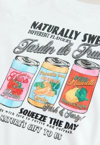 Weißer Stoff zeigt bunte Illustrationen von drei Sodadosen mit Etiketten für Erdbeer-, Orangen- und Birnengeschmack sowie fettem Text.