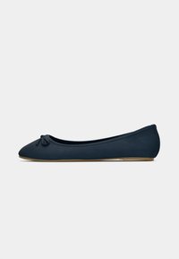 Ballerine blu navy con punta arrotondata, dettaglio di piccolo fiocco sulla parte anteriore e suola piatta marrone chiaro, vista di lato su sfondo bianco.
