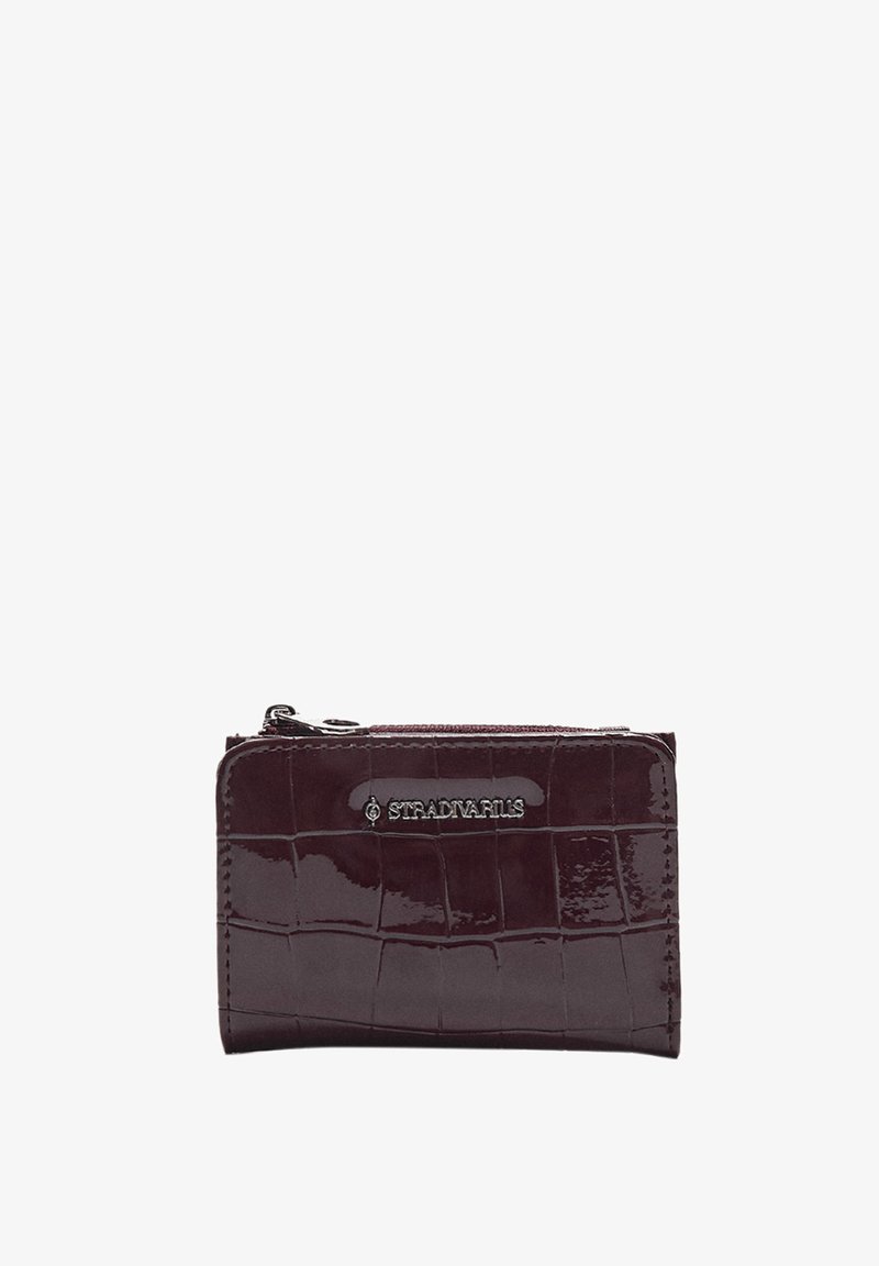 Bordowy portfel z lakierowanej skóry o fakturze krokodyla, z zamknięciem na zamek i srebrnym akcentem logo z przodu.