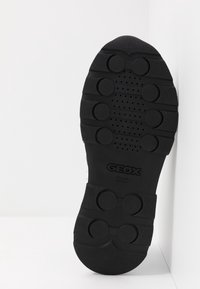 Suola di scarpa in gomma nera con superficie testurizzata, battistrada circolare e fori di ventilazione. Presenta il marchio "GEOX" sul gambetto.