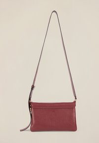 Czerwona skórzana torba crossbody o teksturowanej powierzchni, smukłym kształcie, regulowanym pasku i zamknięciu na zamek. Posiada gładką podszewkę wnętrza.