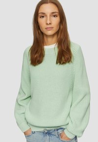 Maglione a maglia verde chiaro con una vestibilità rilassata, polsini e orlo a coste, caratterizzato da una superficie testurizzata e un collo rotondo. Abbinato a un paio di jeans.