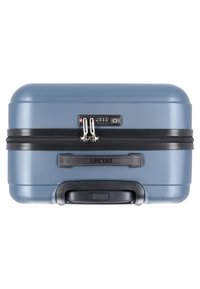 Valigia rigida blu con superficie/texturizzata, zip nera, combinazione di lucchetto e manico telescopico. Nome del marchio "DELEST" sul lato.