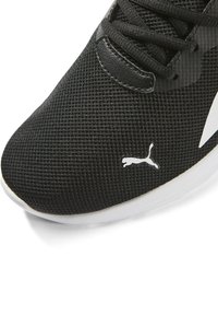 Zapatilla deportiva negra con parte superior de malla texturizada, acentos blancos y un logo. Presenta un diseño de cordones y una suela blanca.