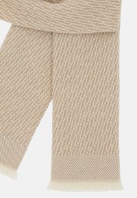 Beige strikket tørklæde med et diagonalt fiskebensmønster, frynsede ender og en blød, struktureret overflade.