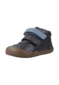 Donkerblauwe leren schoen met een lichtblauwe klittenbandsluiting, gebogen ontwerp, rubberen zool en gestructureerde accenten aan de bovenkant.