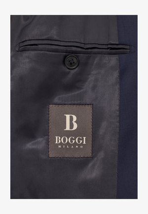 Tessuto di abito blu navale con una superficie liscia, dotato di una tasca a sinistra e un bottone scuro. Include un'etichetta di tessuto grigia con "BOGGI MILANO" in bianco.