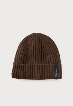 Braune gerippte Strickmütze mit umgeschlagenem Bündchen und kleinem schwarzem Schild mit der Marke Calvin Klein.