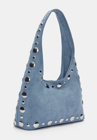 Geantă din suede albastru cu o siluetă curbată, accentuată cu fețe metalice circulare pe margini pentru un aspect decorativ.