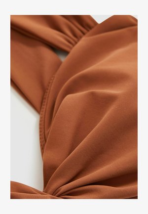 Tessuto marrone con texture e design intrecciato, caratterizzato da un materiale morbido ed elastico. Il primo piano mette in evidenza le pieghe e un accento annodato.