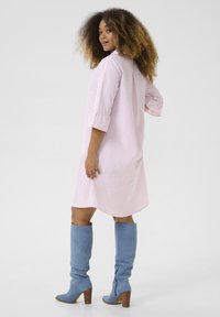 Abito camicia a righe rosa e bianche con una vestibilità comoda e maniche a tre quarti, abbinato a stivali al ginocchio azzurri chiari e tacchi in legno.