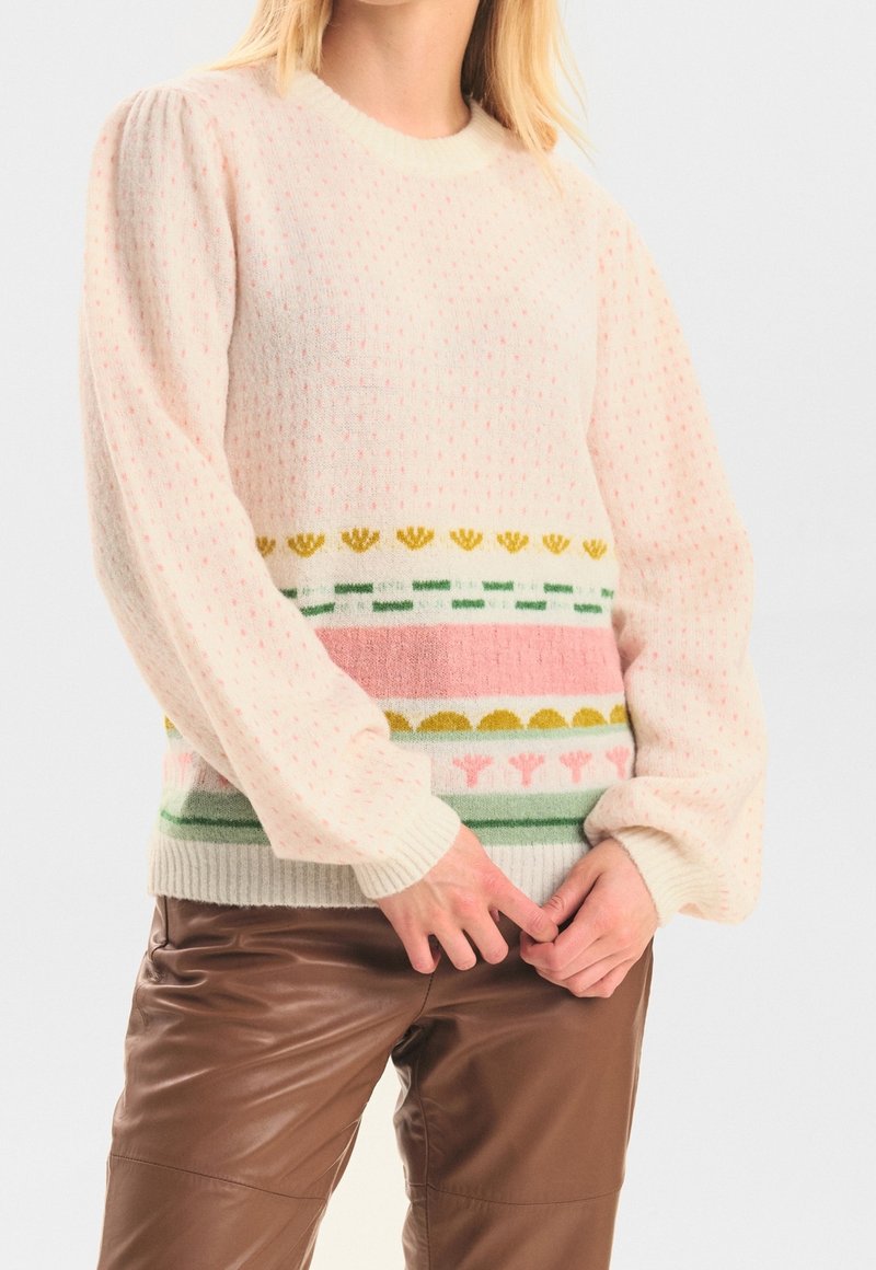Stickad tröja i krämfärg med ett strukturerat mönster och färgglada horisontella ränder, med inslag av rosa, grönt, gult och blommor.