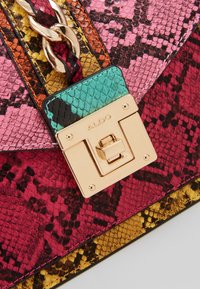 Sac à main coloré à motif peau de serpent avec chaîne dorée et fermoir rectangulaire en or gravé du nom "ALDO".