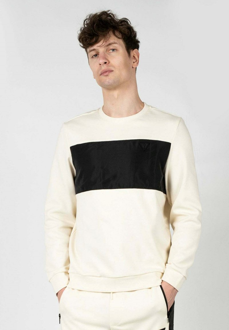 Sudadera de cuello redondo que presenta un cuerpo color crema y un panel horizontal negro en el pecho, elaborada en un tejido suave con una textura sutil.