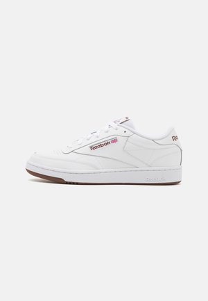 White Reebok sneakers with a smooth texture, featuring a gum sole, lace-up front, and logo accents on the sides and tongue.