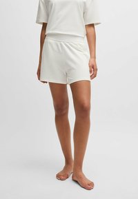 Vita bomullsshorts med resårmidja, med en enkel design och slät yta, som slutar vid mitten av låret. Ingen synlig hårdvara.