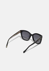 Black sunglasses with a cat-eye shape, gray lenses, and glossy plastic frames. Accented with a decorative design on the temples.