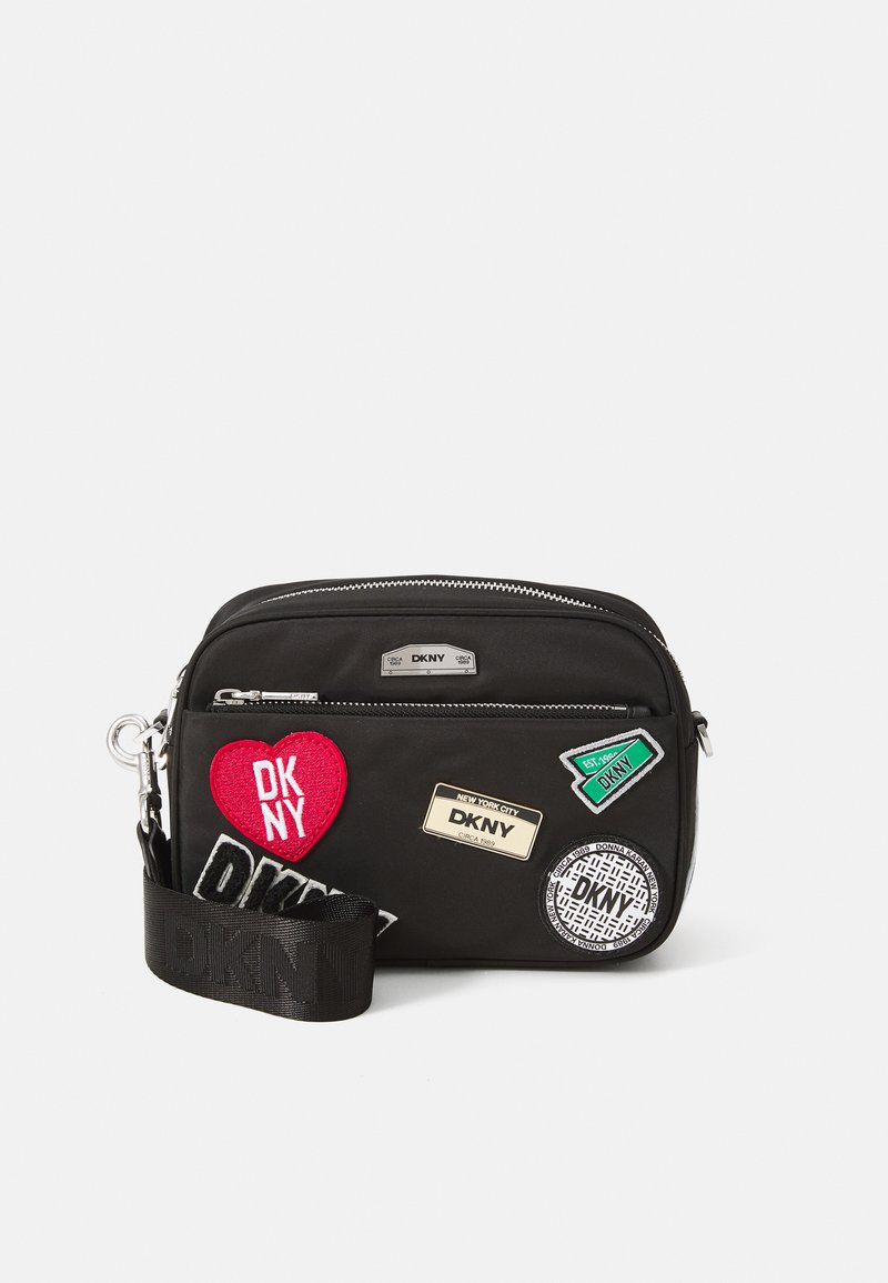 Borsa a tracolla nera in nylon con vari patch: cuore rosso, rettangolo verde, etichetta metallica e disegni circolari. Include una tracolla intrecciata.