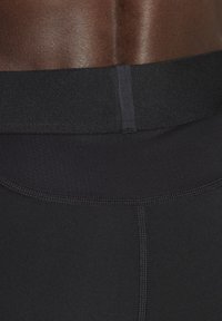 Schwarze nahtlose Sportleggings mit einem breiten Bündchen und glatter Textur, entworfen für Komfort und Flexibilität während des Trainings.