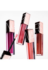 Fire NARS læbepomader i firkantede klare tuber med refleksive sorte og rosaguldfarvede låg. Farverne spænder fra dyb pink til koral og nude. En applikator er synlig.