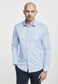 Jasnoniebieska koszula z długim rękawem, z wyrazistym kołnierzykiem, zapinana na guziki, z haftowanym logo na piersi. Wykonana z gładkiego materiału, zaprojektowana w dopasowanym kroju.