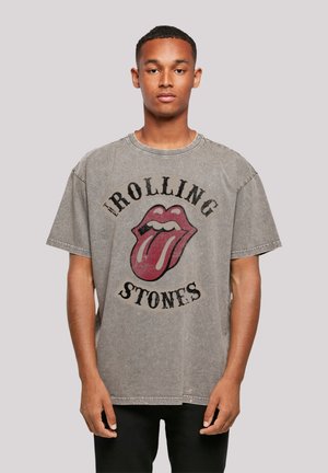 Graues, übergroßes T-Shirt aus Baumwolle mit einem abgenutzten Finish, das ein großes rotes Rolling Stones-Logo in der Mitte der Vorderseite zeigt.