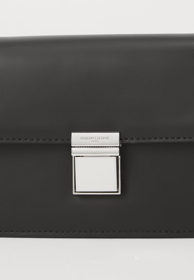 Borsa a mano in pelle nera con chiusura quadrata argentata, design elegante e cuciture minime lungo il bordo. Superficie testurizzata.