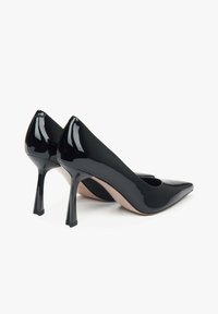 Zwarte lakleren pumps met hoge hakken, een puntige neus en een opvallend, hoekig hakontwerp. Gladde afwerking met minimale accenten.