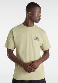 Camiseta de algodón de manga corta en verde claro con el logo "VANS" y un gráfico de llave inglesa en el lado izquierdo del pecho; corte holgado, textura suave.