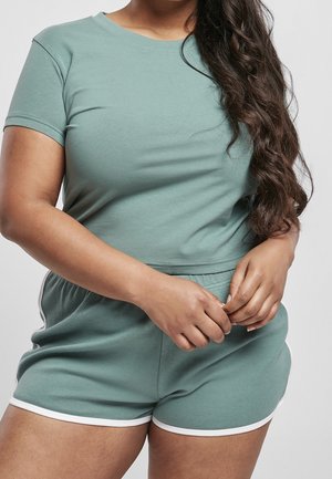 Camiseta de algodón verde y pantalones cortos a juego, con cuello redondo, mangas cortas y ribete blanco en los pantalones cortos, usados de forma casual.