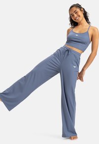 Ensemble deux pièces bleu clair, côtelé, comprenant un crop top ajusté et un pantalon large taille haute avec une ceinture élastique et un accent logo.