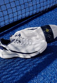 Tenisové boty v bílé a námořnické modři, s texturovaným svrškem, šněrováním a vzorovanou podešví s žlutým akcentem.