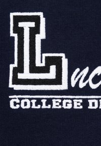 Granatowy sweter z dużą, haftowaną literą "L" w czerni i bieli oraz napisem "COLLEGE DE" poniżej, podkreślający teksturowany, akademicki design.