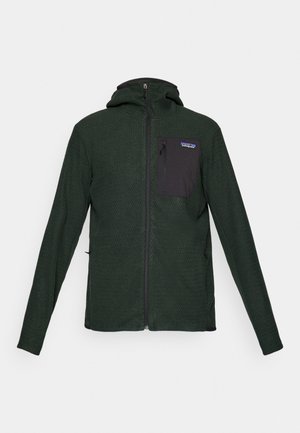 Green textured jacket with a zip front, hood, and a black chest pocket. Features long sleeves and a fitted design.