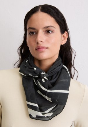 Schwarz-weiß gemusterter Schal aus leichtem Stoff mit einem vorne gebundenen Knoten und einer weichen, transparenten Textur.