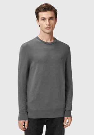 Man wearing plain long-sleeve gray sweater with ribbed cuffs and hem, standing against a neutral background, facing forward.