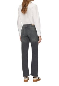 Jean en denim gris à jambe droite avec un design classique à cinq poches, des coutures visibles et une étiquette en simili cuir sur la taille arrière.