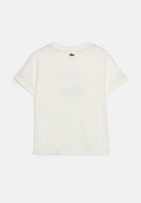 T-shirt en coton blanc, à manches courtes, col rond, avec un petit logo brodé vert à l'arrière. Texture lisse, coupe classique.
