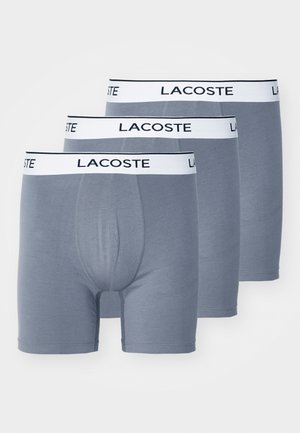 Gray cotton boxer briefs featuring a white waistband with "LACOSTE" logo. Designed for comfort with a classic fit and smooth texture.