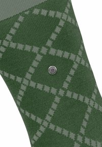 Zielona skarpetka z wzorem w romby w jaśniejszych odcieniach zieleni. Zawiera srebrny akcent logo na materiale.
