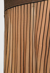Prozirni materijal u toploj bež nijansi, s vertikalnim crnim prugama, teksturiranim finišem i plisiranim dizajnom.