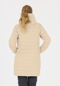 Puffjakke i lys beige med hætte, quiltet struktur, lange ærmer og knælangt snit. Bagansigtet viser en tætsiddende silhuet.