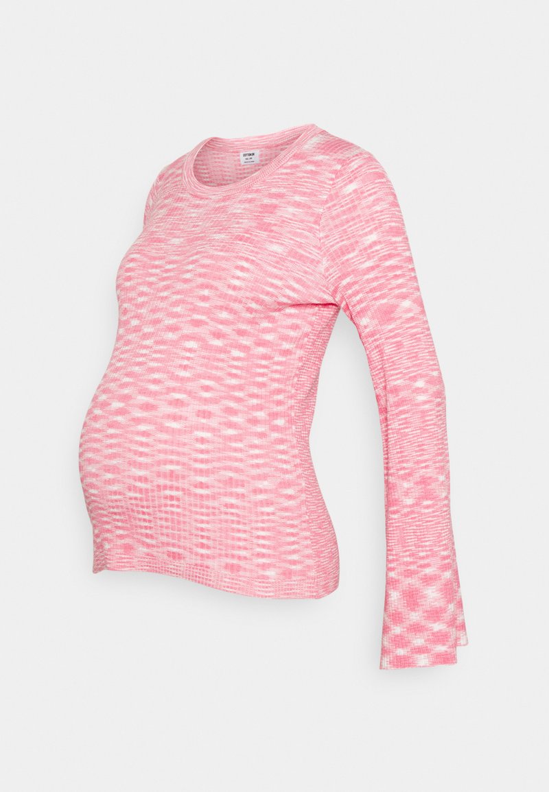 Camisa de maternidade de mangas compridas em rosa com textura branca. Apresenta um decote arredondado e um corpo ajustado, acomodando uma barriga em crescimento.