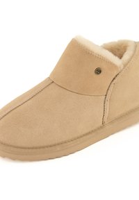 Chausson beige en daim à enfiler, avec une doublure douce en polaire et une semelle en caoutchouc, conçu pour le confort et la chaleur en intérieur.